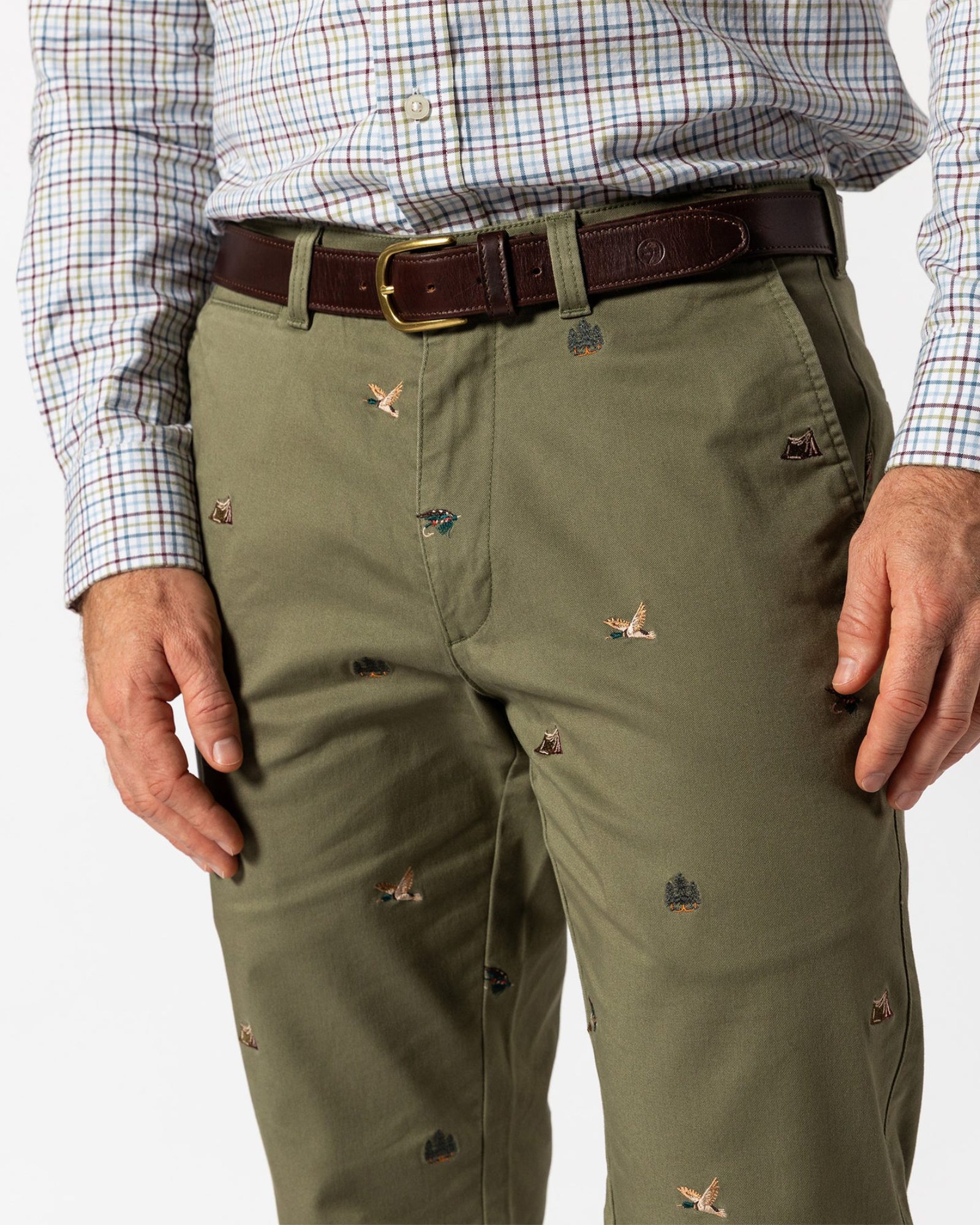 Green pants with small embroidered designs worn by a person, on a white background