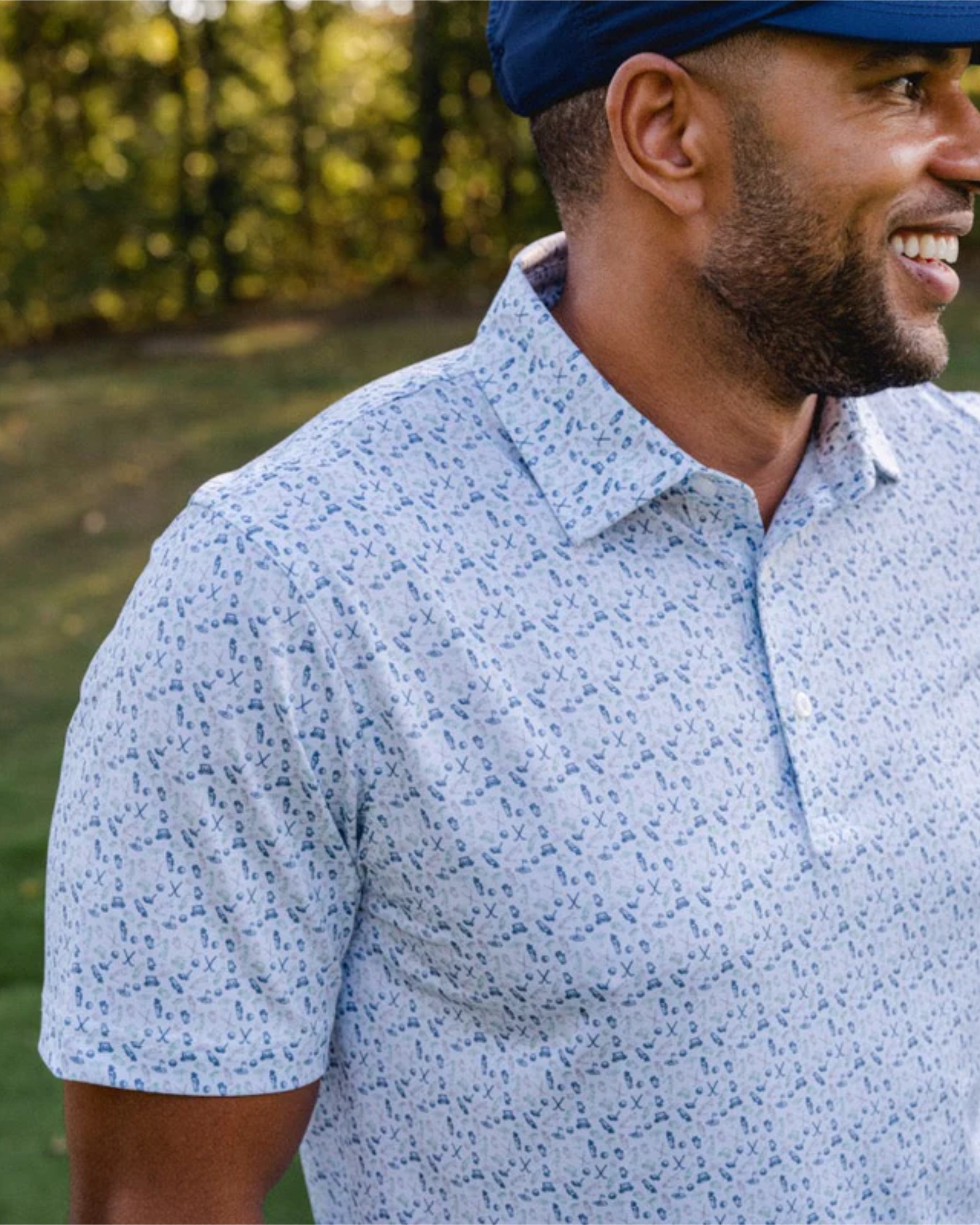 Man wearing a blue patterned shirt and cap outdoors